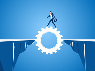 Businessman using cog gear to cross through the gap between hill.  Business risk and success concept.