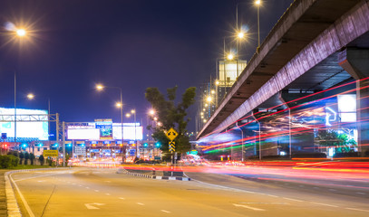 Fototapeta na wymiar Night cityscape view with long traffic light trails at Sinakharin Toll Gate of Sirat Expressway. In Bangkok, Thaiand, Southeast Asia.