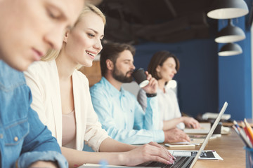 Obraz premium Cheerful youthful girl and coworkers making their job at office