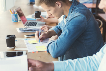 Pensive youthful guy working together with colleagues in office room