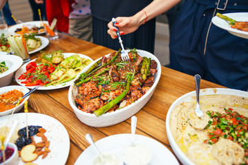 Women's hands pile themselves a meal in a plate of lunch. The concept of nutrition. Buffet. Food. Dinner. The concept of sharing.