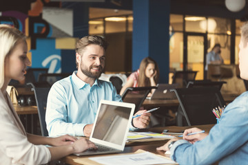 Cheerful youthful males and woman communicating while working in office