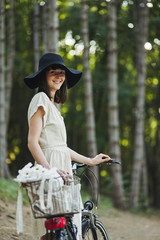 Outdoor portrait of attractive young brunette in a hat on a bicycle.