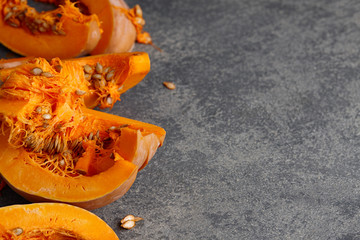 Halloween pumpkin slices with seeds on gray textured stone background