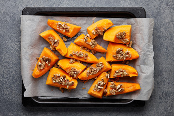 Fresh pumpkin slices with walnuts on baking tray