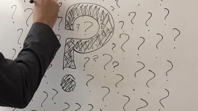 Businessman sketching many question marks on office whiteboard, uncertainty and unpredictability in business