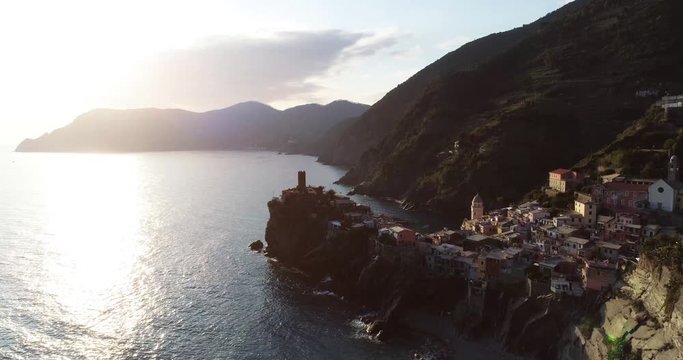 aerial view of travel landmark destination Vernazza, a small mediterranean sea town, Cinque terre National Park, Liguria, Italy. Sunset with cloud and flare. 4k aerial drone up video shot