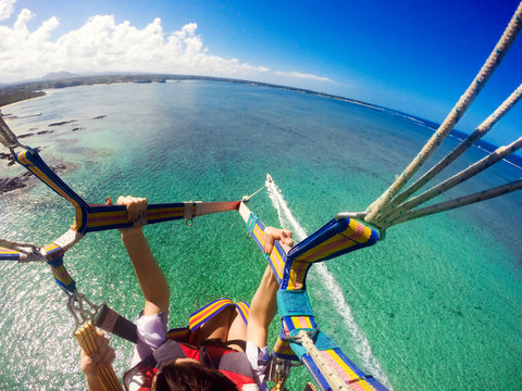 View of couple parasailing with the speed boat in the sea background.