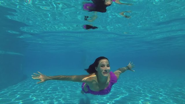Young beautiful woman swims under water in the pool
