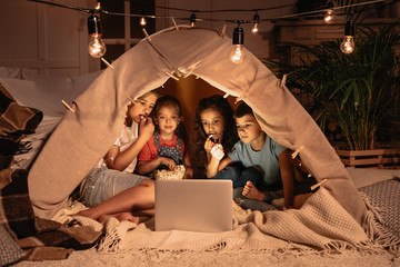 little multiethnic kids sitting tent and watching film together on laptop © LIGHTFIELD STUDIOS
