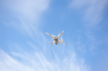Fototapeta na wymiar Quadcopter or drone holds video using a digital camera on the blue sky background