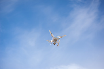 Quadcopter or drone holds video using a digital camera on the blue sky background
