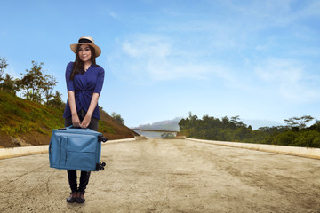 Pretty asian traveler with hat holding suitcase