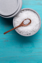 Sea salt in an stone bowl with small wooden spoon on a blue wooden table