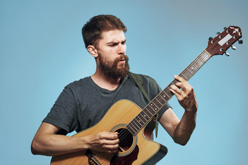 Young guy with a beard on a blue background playing the guitar