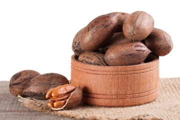 pecan nuts in a wooden bowl on the old board with white background