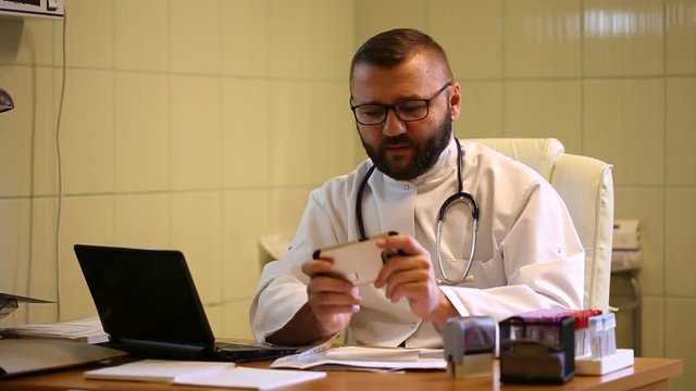 Doctor having a break in work and playing games on smartphone
