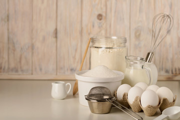 Kitchen utensils and tools for homemade baking on a light wooden background.