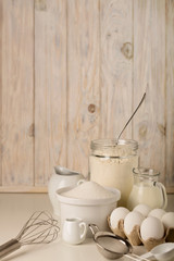 Kitchen utensils and tools for homemade baking on a light wooden background.