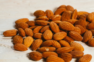 handful of almonds on a white wooden background