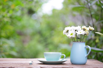 Coffee in blue cup with white flower in blue pot