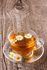 Herbal tea with fresh chamomile flowers on old wooden background with copy space for your text