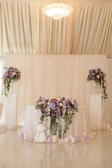 Wedding table decoration in ivory and lilac colors with the initials of the fiance and fiancee as the coat of arms