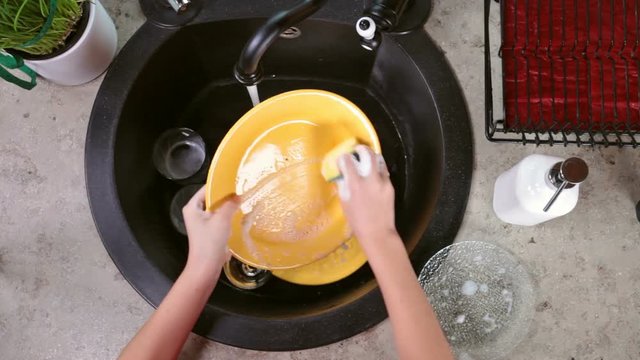 Child hands washing dishes - top view of the kitchen sink area