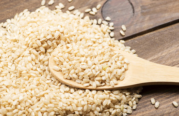 Wooden spoon with rice on wooden table.