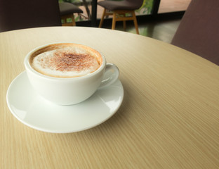 Hot latte in white cup put on wood table in coffee cafe.