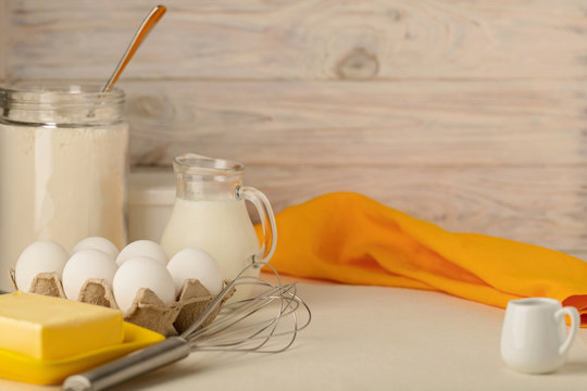 Kitchen utensils, tools and products for homemade cakes on a light wooden background.