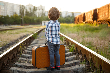 Boy with suitcase standing on railways