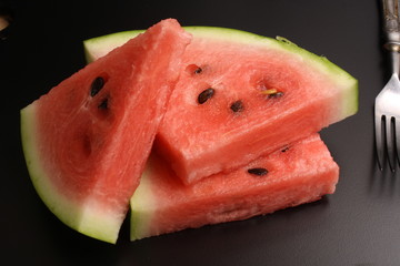 Watermelon on a black background, fork and rope