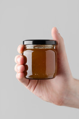 Apricot Jam Jar Mock-Up - Male hands holding a jam jar on a gray background