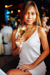 Attractive young girl holding a glass and drinking martini with lemon cocktail