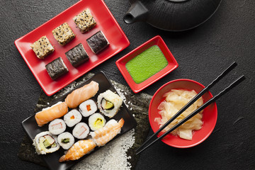 Sushi set and black teapot on black table
