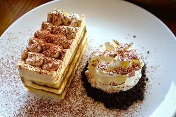 Tiramisu, traditional Italian dessert with whipping cream on  white plate