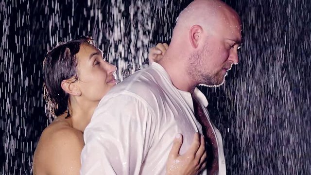 big, bald man feels resentment towards his beloved woman lowered her head down and thought. she's behind his big back and doesn't let go. the relationship between the people in the rainy sad day