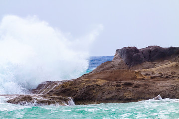 Fototapeta na wymiar Big waves crashing against of the rocks.