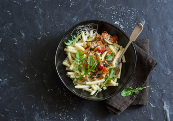 Vegetarian pasta with steamed vegetables on dark background, top view