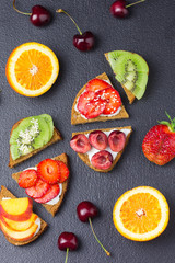 Sweet fruit bruschetta on black concrete background.  Top view .