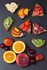 Various colorful friut toasts with mascarpone on black background.  Top view.