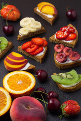  Various fruit sandwiches on black stone background.  Selective focus