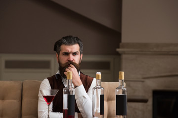 Obraz premium Hipster sitting at table with three bottles and glass