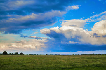 Beautiful clouds in blue sky and field in countryside. Summer rural landscape.