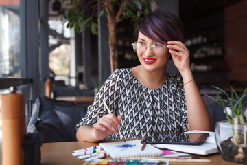 Charming girl painting at table