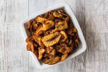 Dried Carrot Chips on white wooden surface.