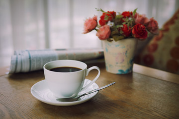Cup of coffee with newspaper on the table in the morning , warm tone background