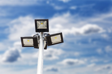 Street LED Light with energy-saving technology on the pole against blurred blue cloudy sky