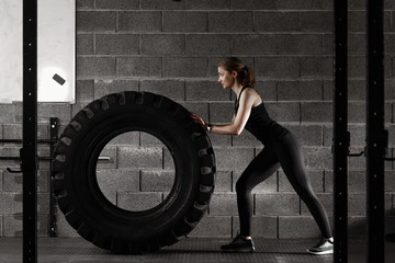 Fototapeta na wymiar Fit female flipping tire at the gym.